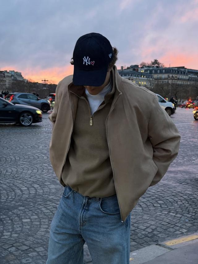 beige zip-up jacket over white mock neck and blue jeans