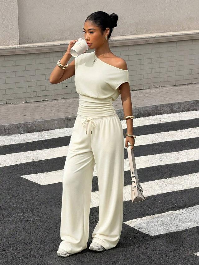 cream asymmetric neck cinched waist top and loose trousers