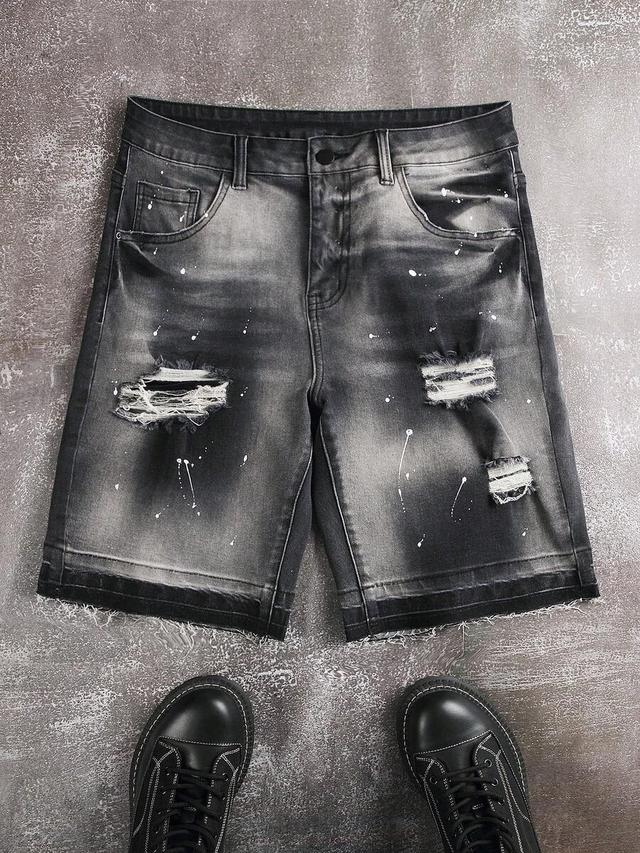 distressed black denim shorts with paint splatter effect