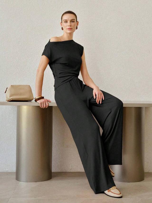 black ruched asymmetric knit top and wide-leg trousers