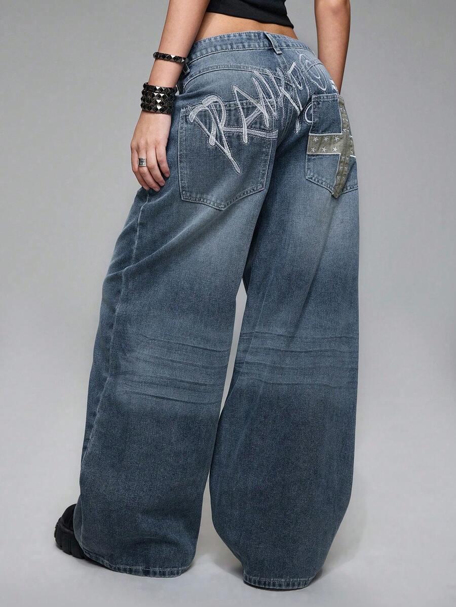 distressed wide leg jeans with embroidered cross and lettering