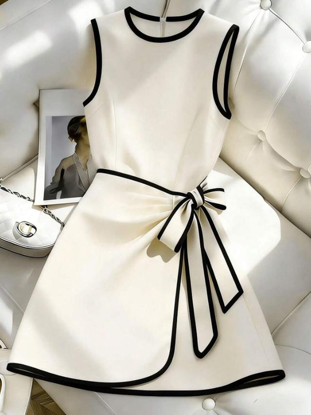 cream sleeveless dress with black contrast piping and bow