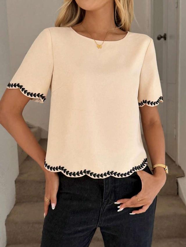 cream short sleeve top with black embroidered ribbon trim