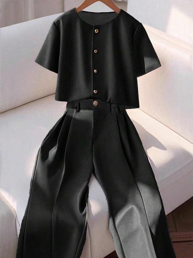 black short sleeve button-up shirt and pleated trousers