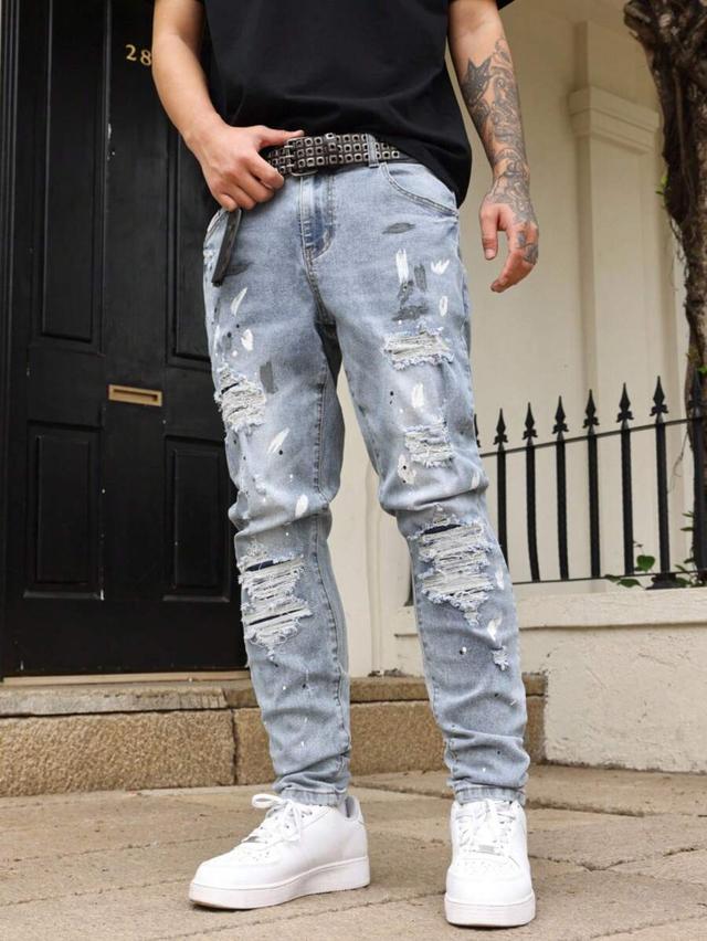 distressed light wash denim jeans with paint splatter