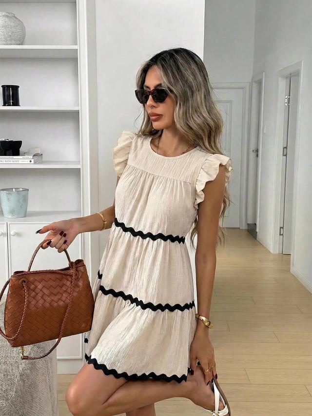 beige textured tiered dress with black rickrack trim