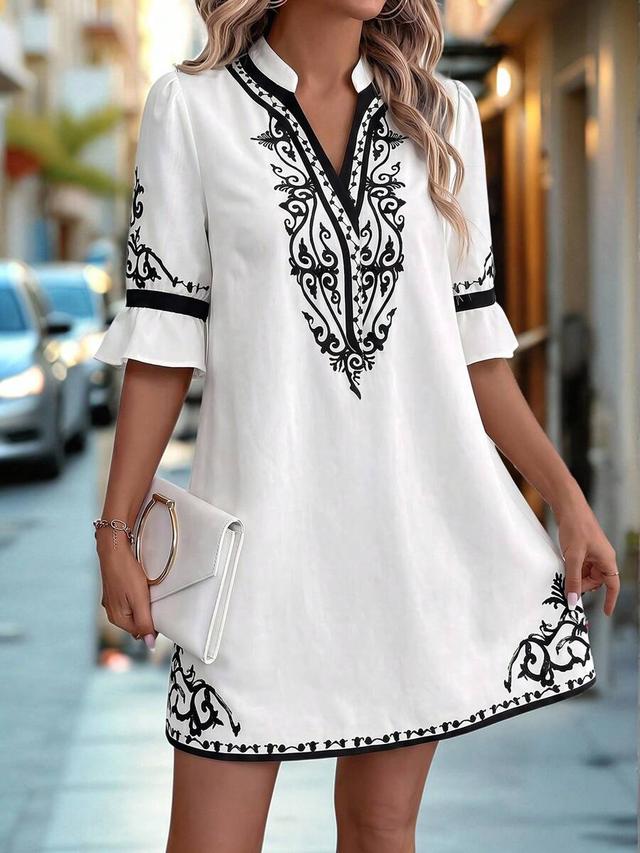white shift dress with black scroll embroidery